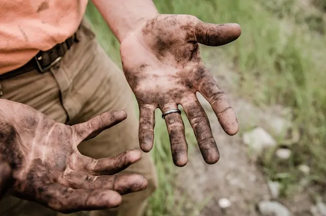 Mãos de um produtor sujas de terra
